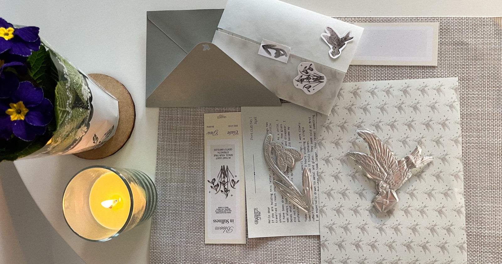 Graphite Post package flatlay with flowers and candle